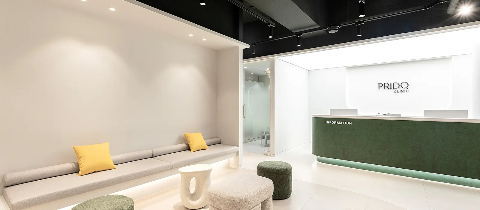Waiting lounge at PRIDQ Clinic with a long bench, cushions and the green reception desk