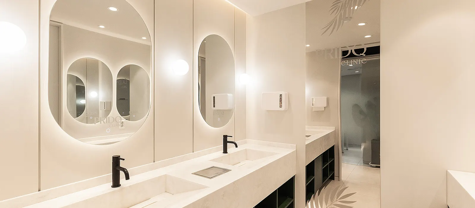 Powder room with stone vanity and backlit oval mirrors