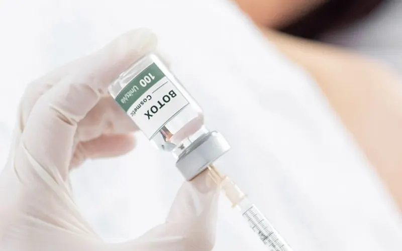 Botox vial and syringe held by a gloved hand